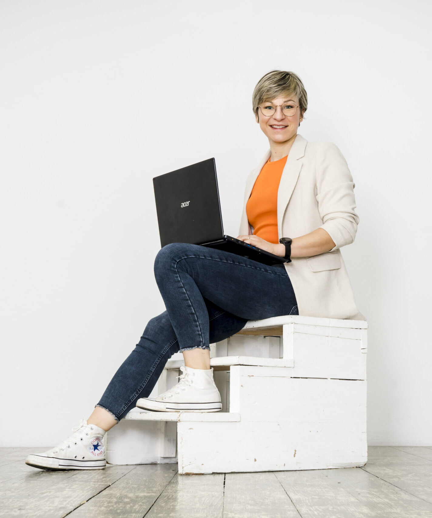 Dr. Lisa Schwarzinger sitzt mit Notebook auf einer Treppe